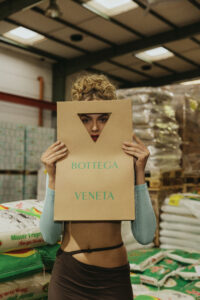 Model hält Papiertüte von Bottega Veneta vor ihrem Körper